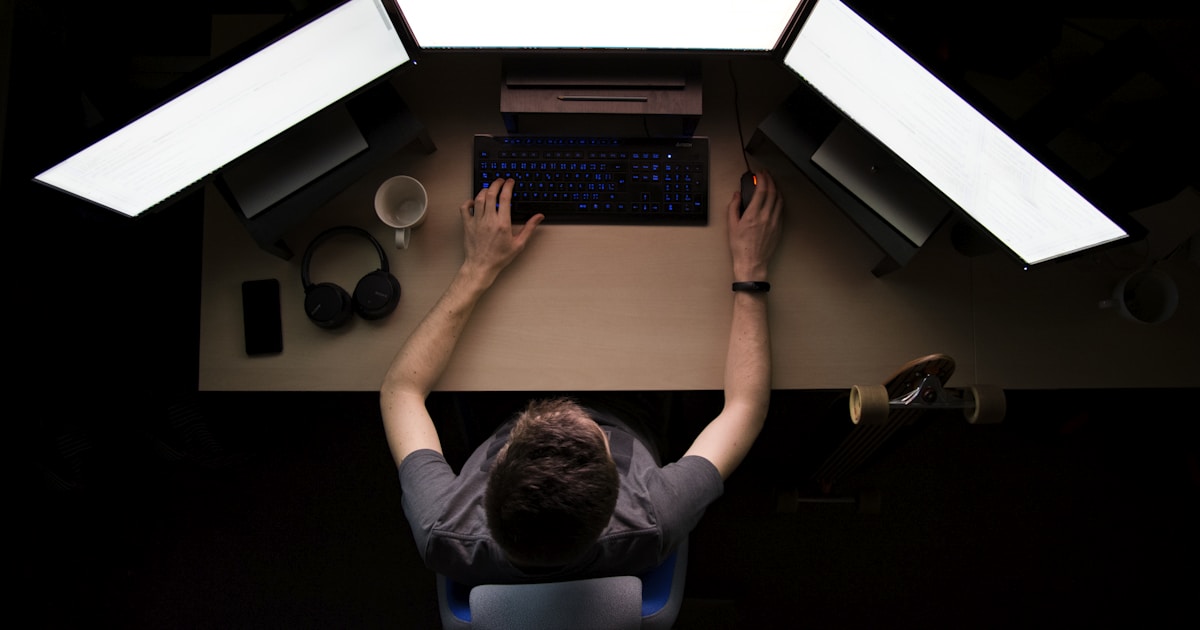 Pantalla de código fluorescente en escritorio oscuro